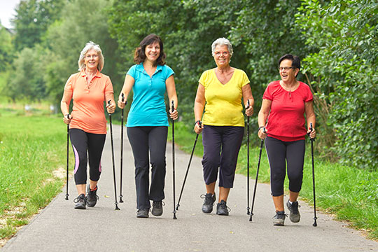 Vier Frauen beim Nordic-Walking mit Wanderstöcken