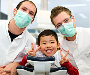 Kind Zahnarztstuhl mit zwei Zahnärzten