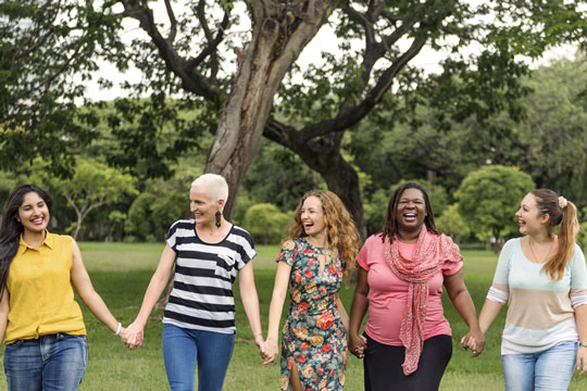 Frauengruppe hält sich an den Händen draußen Frauengruppe hält sich an den Händen draußen