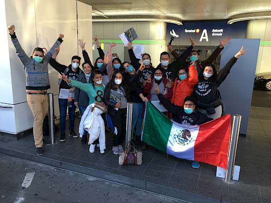 Gruppe fröhlicher Personen mit mexikanischer Flagge am Flughafen