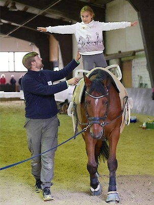 Kind auf einem Pferd, Erwachsener passt auf