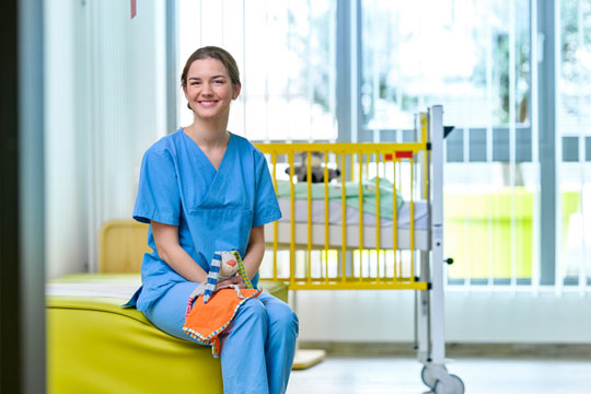 Pflegerin mit Kuscheltier in Krankenzimmer