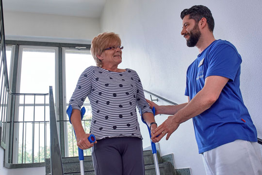 Physiotherapeut mit Patientin beim Treppensteigen Physiotherapeut mit Patientin beim Treppensteigen