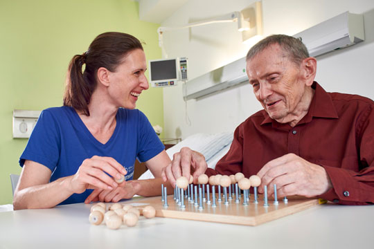 Physiotherapeutin mit Patient bei Motorikübung Physiotherapeutin mit Patient bei Motorikübung